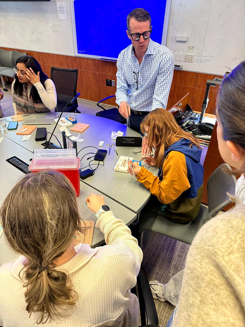 Educator demonstrating surgical suturing at a practice station
